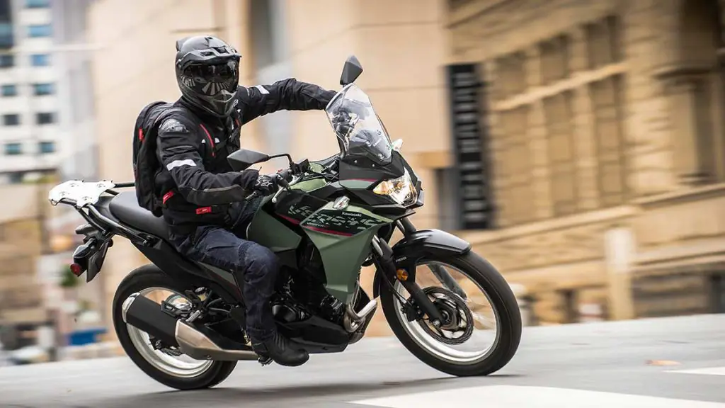 A man riding a Kawasaki Versys X-300 in a paved road in a city