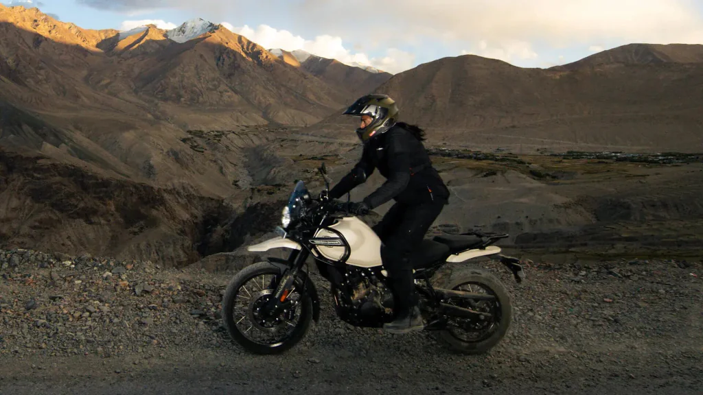 A man riding a Royal Enfield Himalayan in a paved road in a desert mountain