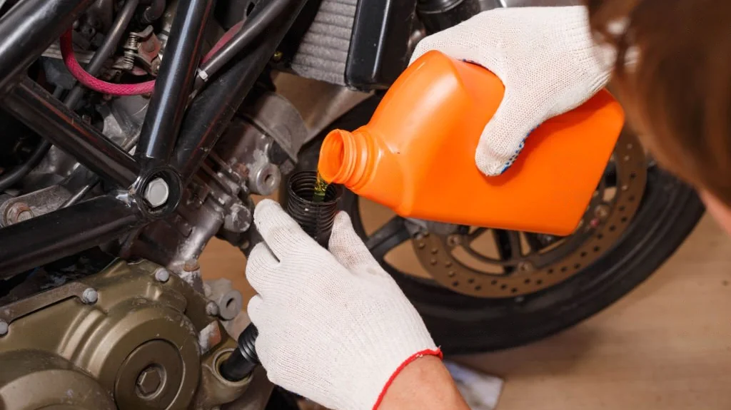 image of a person changing the engine oil of an motorcycle