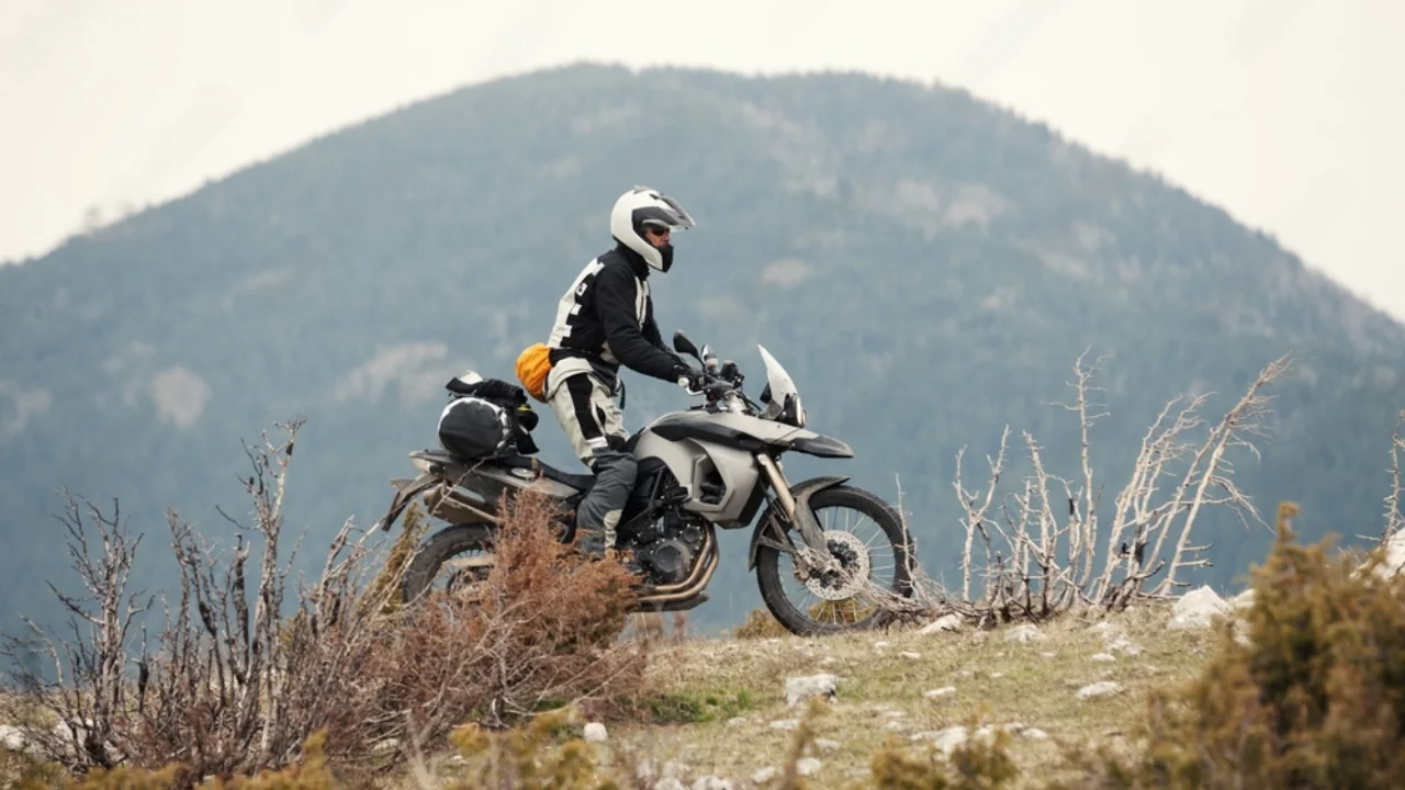 Image of an adventure motorcycle at the top of a hill with a rider standing on it